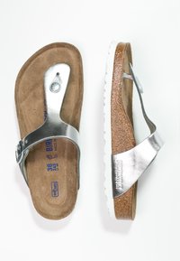 Sandales en cuir argenté avec une semelle intérieure en cuir texturé marron, une boucle ajustable et une semelle en caoutchouc texturé blanche. Taille 38.