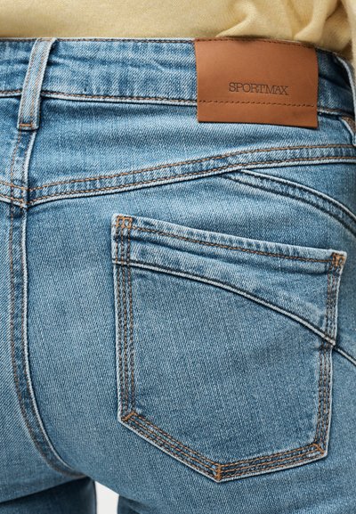 Οπίσθια όψη ανοιχτό μπλε τζιν με πορτοκαλί ραφές και καφέ δερμάτινη ετικέτα με την επιγραφή "SPORTMAX" στην περιοχή της μέσης.
