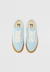 Light blue canvas sneakers with white accents, round laces, and a gum rubber sole. Features a padded collar and soft interior lining.