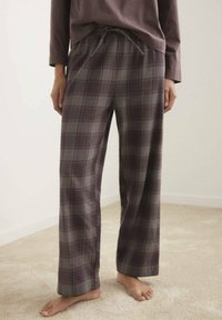 Pantaloni del pigiama scozzesi in viola scuro e grigio, con vita regolabile, vestibilità comoda e tessuto morbido, indossati a piedi nudi.