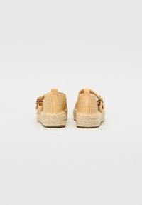 Tan színű, szőtt espadrille cipők texturált szövet felsőrésszel, jutaszálas talppal és csat részletekkel a sarkán. Simafon színű bőrdíszítések.
