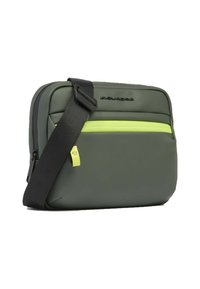 Borsa a tracolla sintetica verde con tracolla nera regolabile, dotata di una tasca frontale con zip gialla brillante e superficie strutturata.