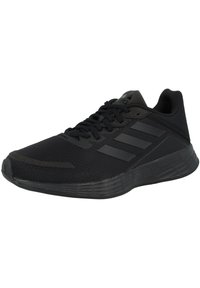 Chaussure de sport noire avec une tige en mesh, semelle texturée et trois bandes noires sur le côté. Caractéristiques : une pointe arrondie et un design à lacets.