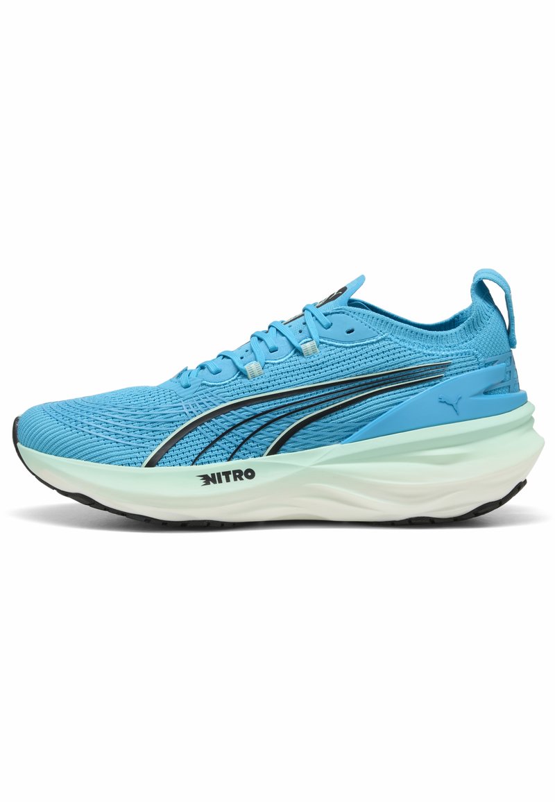 Zapatillas de correr de color azul claro con parte superior de malla texturizada, acentos negros, suela blanca acolchada y una lengüeta en el talón para facilitar el uso.