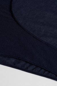 Marineblåt elastisk stof med en glat tekstur; har en afrundet hals og et sømløst design med fine sømme langs kanterne.