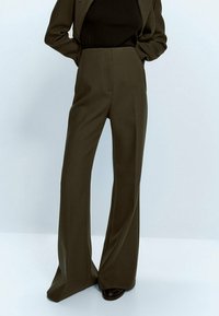 Pantalons taille haute vert olive avec une coupe large, fabriqués en tissu structuré, présentant des plis avant nets et une taille sans couture.