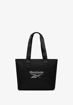 Czarna torba Reebok typu tote z podwójnymi uchwytami, przednią kieszenią na zamek oraz odblaskowym logo umieszczonym poniżej kieszeni.
