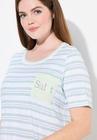 T-shirt a righe in verde, bianco e lavanda, con una tasca menta dove è ricamato "Salut" in lettere colorate. Design morbido e casual.