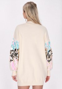 Cremfarbener Pullover mit langen Ärmeln, verziert mit Pailletten in Blau, Rosa und Gold, mit einem gerippten Rundhalsausschnitt und Bündchen.