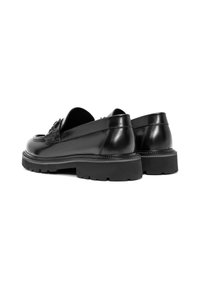 Mocasines de cuero negro con un upper texturizado, punta redondeada y suela de goma gruesa con un perfil pronunciado para mejorar el agarre.
