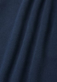 Navyblaue Stoff mit einer weichen, feinen Textur, die subtile Falten und eine glatte Oberfläche aufweist, was auf ein hochwertiges Textilmaterial hinweist.