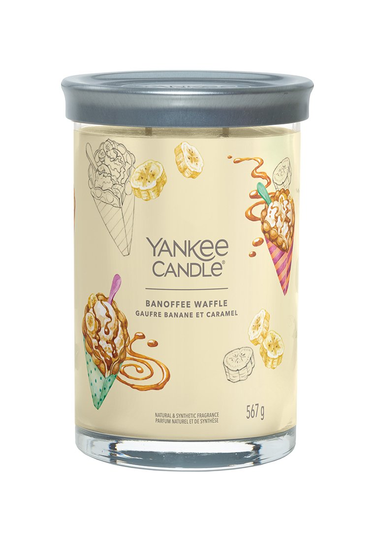 Tarro de vela de vidrio con tapa metálica, etiquetado como "Waffle de Banoffee". Presenta ilustraciones de plátanos, caramelo y conos de helado en colores pastel.