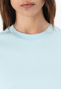 Lyseblå bomulls T-skjorte med rund hals og brodert "Calvin Klein"-logo i en subtil tone, som har en glatt tekstur.