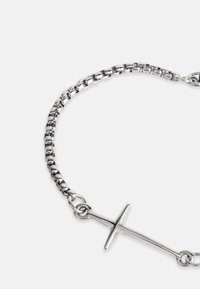 Sidabrinė grandinėlė su paprastu kryžiaus pakabuku, su lygiomis grandinėmis ir blizgiu paviršiumi. Kompaktiškas dizainas su minimaliais dekoratyviais elementais.