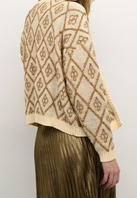 Stickad cardigan i beige med brunt diamantmönster, med ribbade mudd och nederkant. Matchas med en plisserad kjol i metalliskt guld.