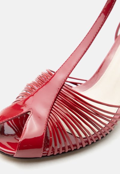 Κόκκινο λουστρίνι τακούνι σανδάλι με ανοιχτό δάχτυλο και πολλαπλές λεπτές οριζόντιες λουρίδες κατά μήκος των πλευρών.