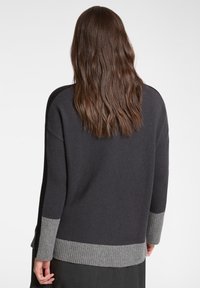 Grauer gestrickter Pullover mit lockerem Schnitt, mit gerippten Bündchen und Saum sowie kontrastierendem hellgrau am Saum und an den Bündchen.