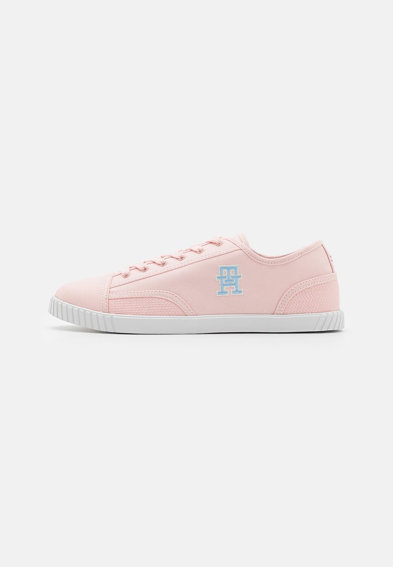Pink canvas sneakers with white rubber soles, featuring a textured side panel and light blue logo on the outer side. Classic lace-up design.