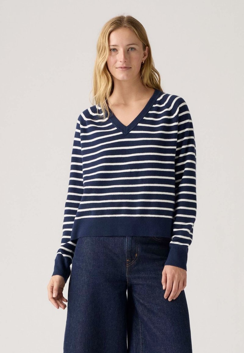 Maglione a righe blu navy e bianche con scollo a V, maniche lunghe e orlo corto. Tessuto morbido con polsini e vita a coste.