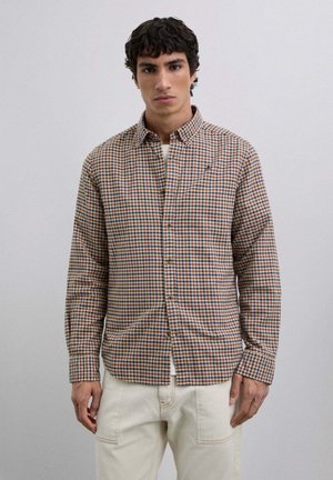 Camisa de botones a cuadros en naranja, marrón y azul. Tela de algodón con mangas largas y cuello puntiagudo. Detalle de bolsillo en el frente.