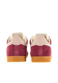 Maroon suede sneakers with a light beige heel and white accents. Textured sole in light brown rubber. Rounded design with stitched details.