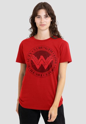 Red cotton t-shirt featuring a black circular graphic with text and stylized 'W' logo at the center. Short sleeves and round neck design.
