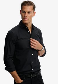 Zwarte longsleeve shirt met een button-down kraag en witte knopen. Kenmerkt rode accenten aan de binnenkant van de kraag en mouwen, gladde stof.