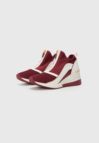 Sneaker alte rosse e bianche con design high-top, dotate di tomaia in mesh, dettagli in zip dorati e suola a zeppa. Dettagli testurizzati sui lati.