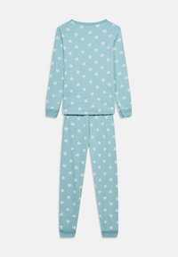 Σετ παιδικής πιτζάμας με ανοιχτό μπλε μπλουζάκι μακρυμάνικο και παντελόνι, διακοσμημένο με λευκές καρδιές με ρίγες, εμφανίζεται από πίσω.