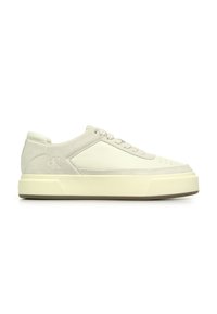 White sneaker made of leather and suede, featuring a textured upper, rounded toe, and thick rubber sole with minimal branding.