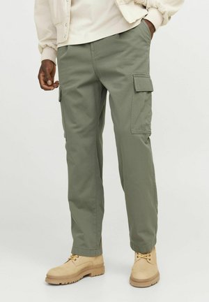 Cargo broek in lichtolijfgroene stof, met zijzakken, rechte pasvorm, en gedragen met tan kleurige laarzen. Zachte textuur, casual ontwerp.