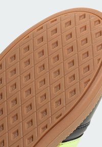 Rubber outsole with a textured, diamond-pattern surface. Brown color with orange accents. Features a serrated edge for grip and durability.