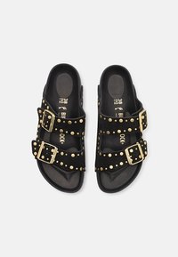 Sandales Birkenstock noires avec deux lanières ajustables ornées de clous dorés et boucles, taille 38, présentées sur un fond blanc.