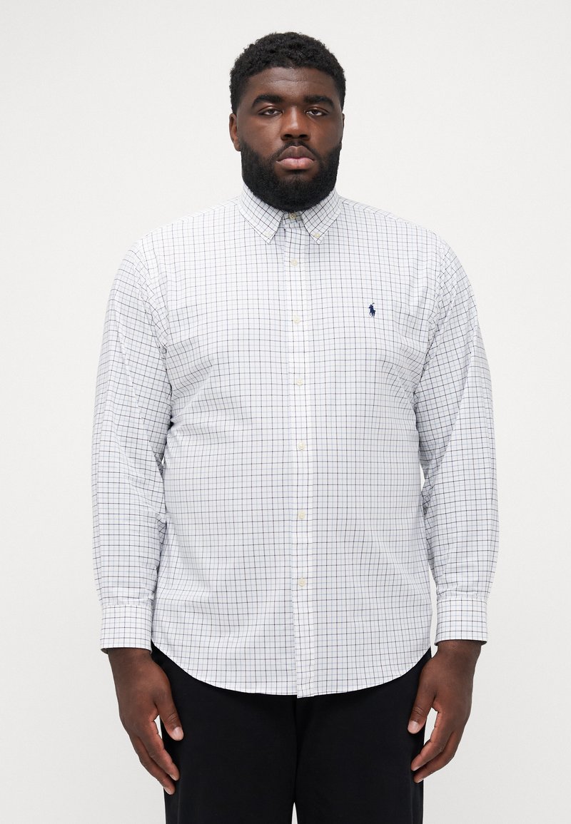 Chemise blanche à manches longues avec un motif à carreaux bleu et rouge, col boutonné et petit logo brodé sur la poitrine. Tissu en coton.