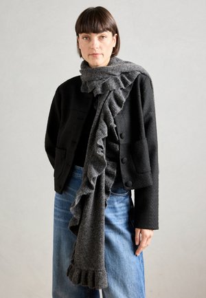 Gray ruffled scarf wrapped around the neck, paired with a black jacket and light blue jeans. Textured wool fabric, casual fit.