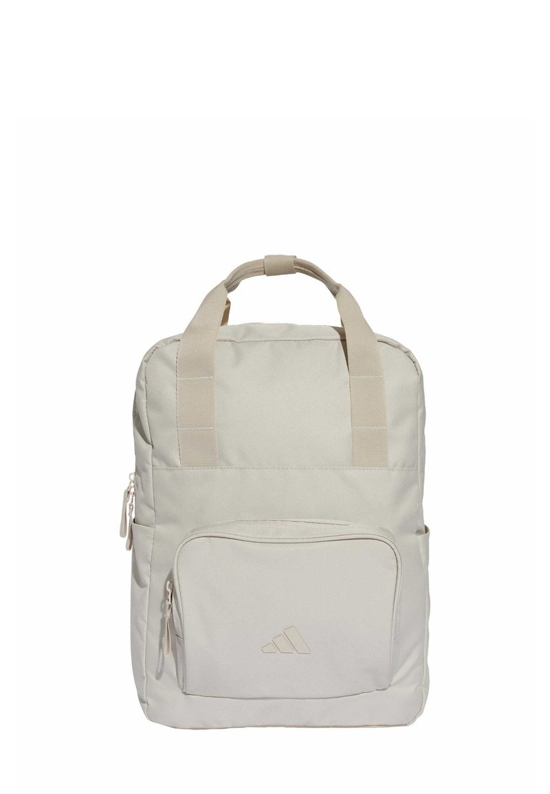 Mochila de color beige claro hecha de tela, con dos asas superiores, un bolsillo frontal con cremallera y un detalle de logo en relieve en la base.