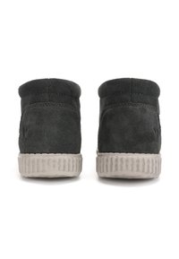 Bottines en suède noir avec un bout rond, dotées d'une semelle en caoutchouc gris texturé et de coutures discrètes à l'arrière.