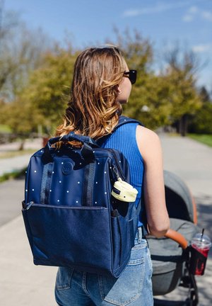 Navy blue backpack with white polka dots, multiple pockets, and textured fabric. Includes a yellow accessory attachment on the side.