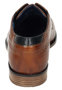 Chaussure en cuir avec une finition marron, un col en relief noir et des détails perforés subtils. Dispose d'une semelle durable avec une légère biseautage.