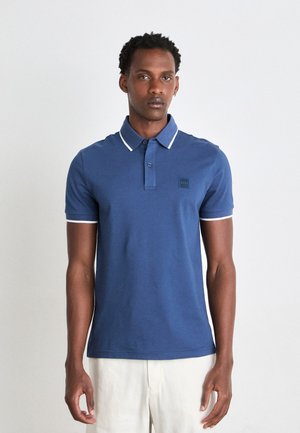 Blue polo shirt with white trim, featuring a two-button placket, short sleeves, and a subtle brand logo on the chest. Smooth cotton texture.