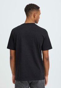 Sort bomuld t-shirt med rund halsudskæring, korte ærmer og en afslappet pasform. Baghjørnet viser glat tekstur og enkel design.