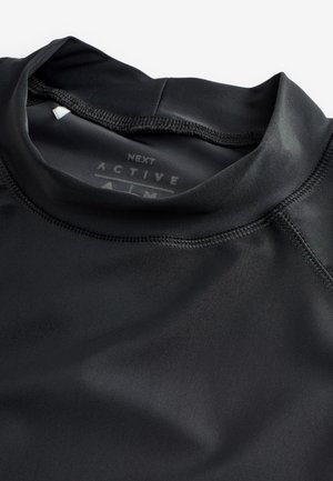 Zwarte sporttop gemaakt van glad, rekbaar materiaal. Voorzien van een hoge kraag en flatlocknaden voor comfort en duurzaamheid.