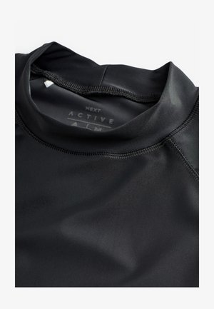Zwarte sporttop gemaakt van glad, rekbaar materiaal. Voorzien van een hoge kraag en flatlocknaden voor comfort en duurzaamheid.