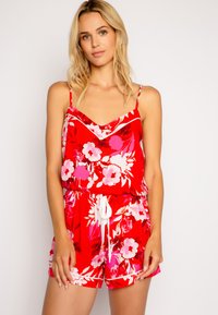 Röd blommig jumpsuit med V-ringning, spagettiband, elastisk midja med dragsko och vita detaljer på ärmarna och shortsen.