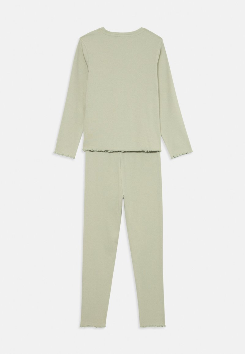 Weiches, hellgrünes, geripptes Langarmoberteil und passendes, hochgeschnittenes Leggings-Set mit einen Salatkantensaum an Ärmeln, Taille und Knöcheln.