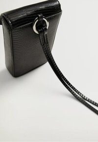 Černá kabelka s kroko vzorem v obdélníkovém tvaru a stříbrným kroužkem jako akcentem. Obsahuje dlouhý, tenký popruh na nošení.