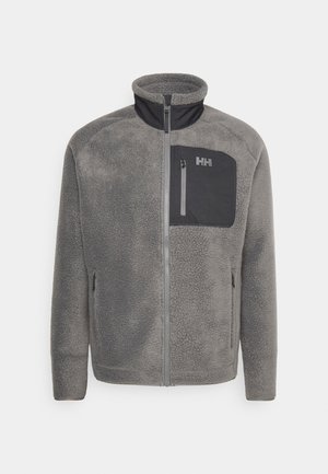 Gray fleece jacket with a high collar, black zippered chest pocket, and side pockets. Features a textured fabric and contrasting colors.