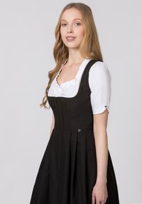 Black traditional dress with a fitted bodice and full skirt, featuring a white blouse with ruffled neckline and button accents.