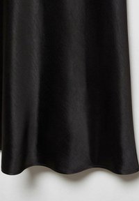 Tissu en soie noire suspendu, présentant une texture lisse et un léger lustre. Le bord inférieur a un ourlet ondulé subtil, ce qui met en valeur le tombé.