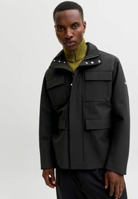 Čierna vodoodolná bunda s vysokým golierom, dvoma prednými vreckami na klopu a patentnými gombíkmi. Hladká textúra a minimalistický dizajn.